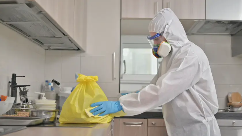 Technician in full protective equipment disinfecting a contaminated room in a Newcastle property